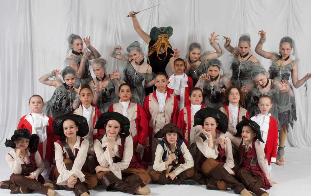 Twenty-four dancers in Pirate of the Caribbean costumes posing for a photo